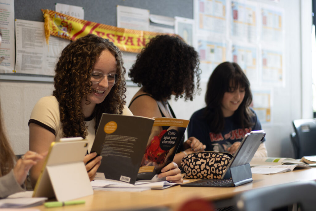 A Level Spanish lesson in St David's Catholic Sixth Form College with student smiling whilst reading from textbook