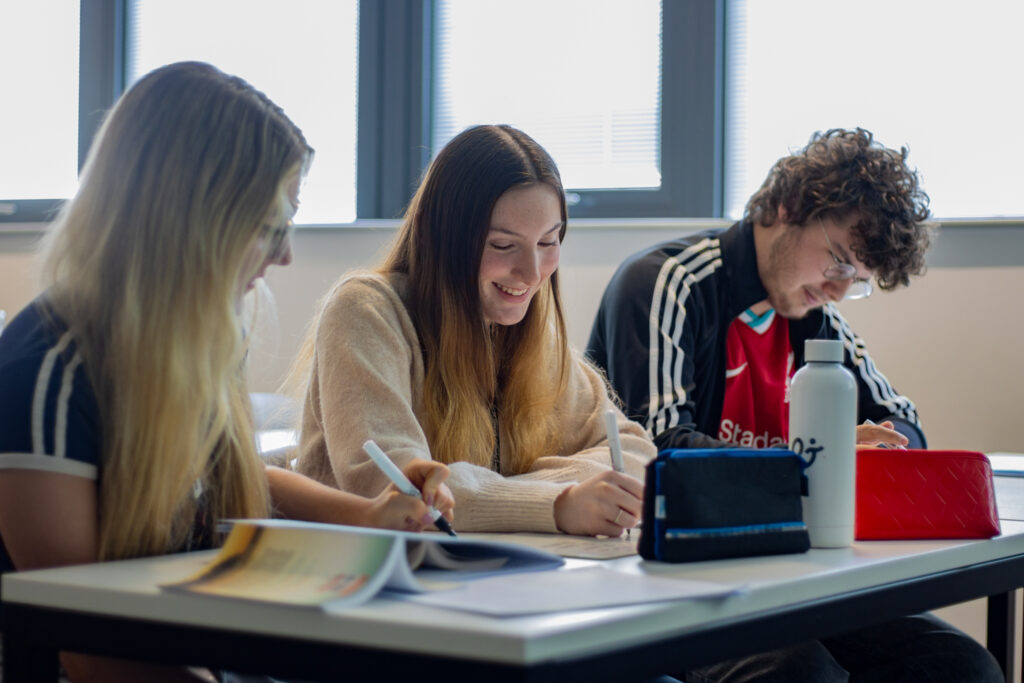 A Level French lesson in St David's Catholic Sixth Form College with a student smiling with others whilst scribbling down notes