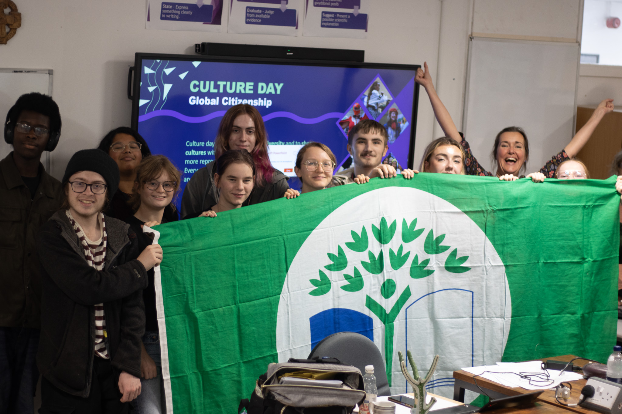 Students standing behind a green flag